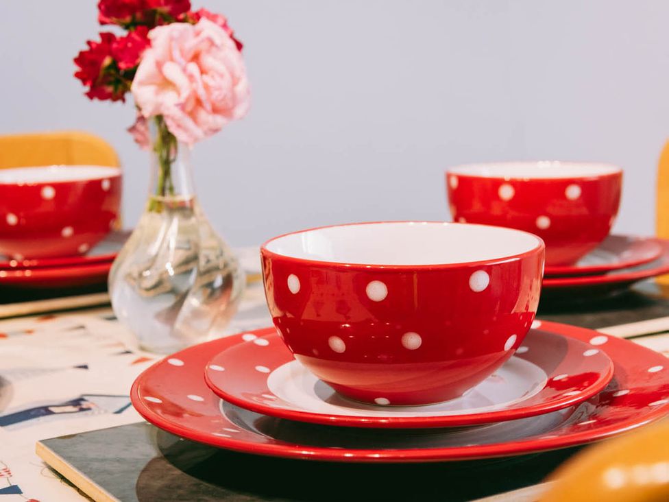 A dining table set with red polka dot bowls and plates at 1 Bed Sleeps 3 Free Parking Pets Allowed in Dereham
