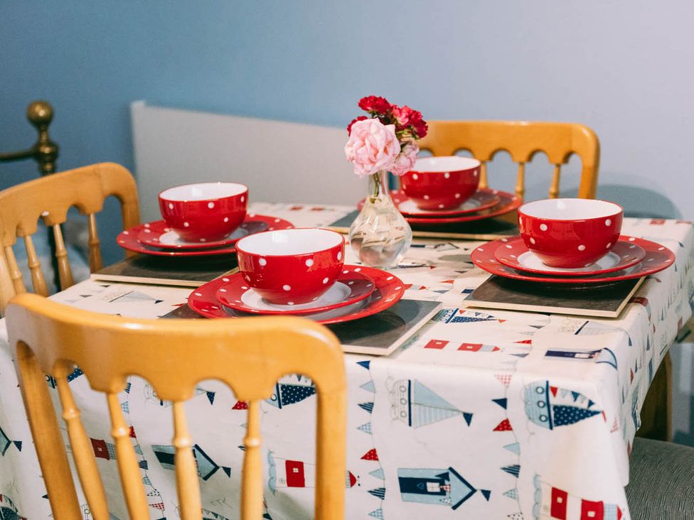 A dining table set with red bowls and plates at 1 Bed Sleeps 3 Free Parking Pets Allowed in Dereham