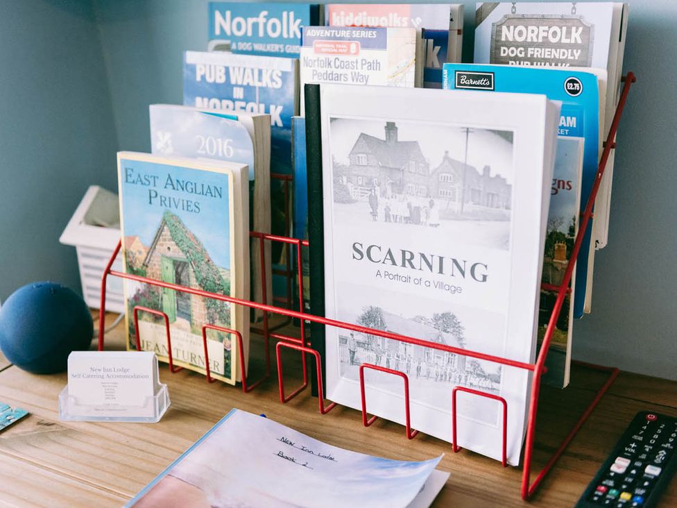 A collection of books and brochures on a wooden table at New Inn Lodge in Dereham