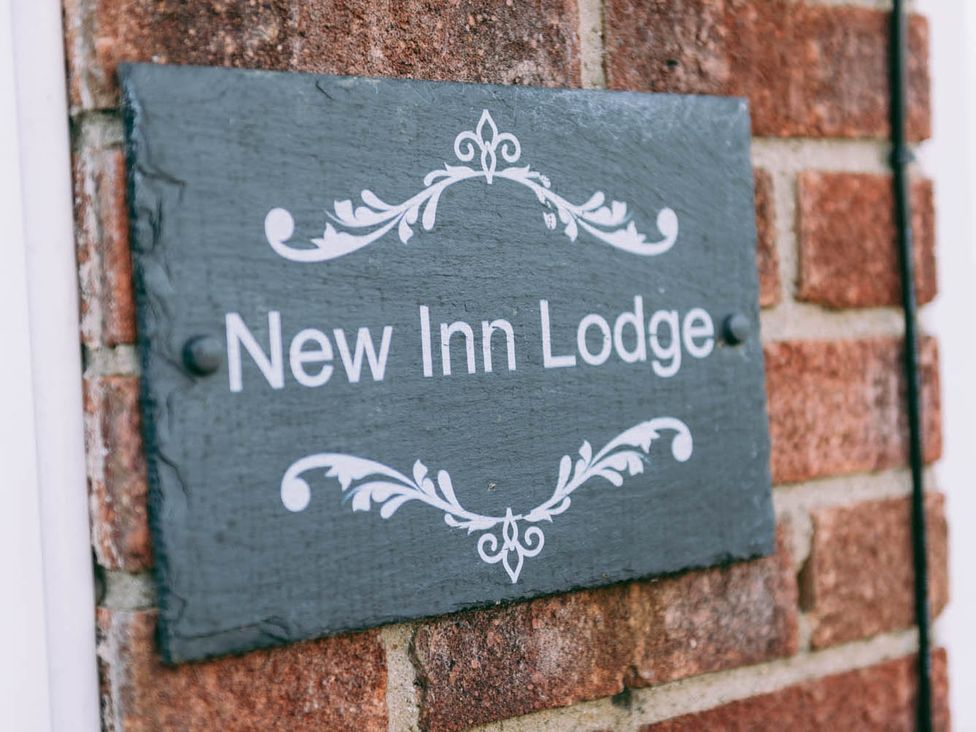 A sign for New Inn Lodge on a brick wall in Dereham