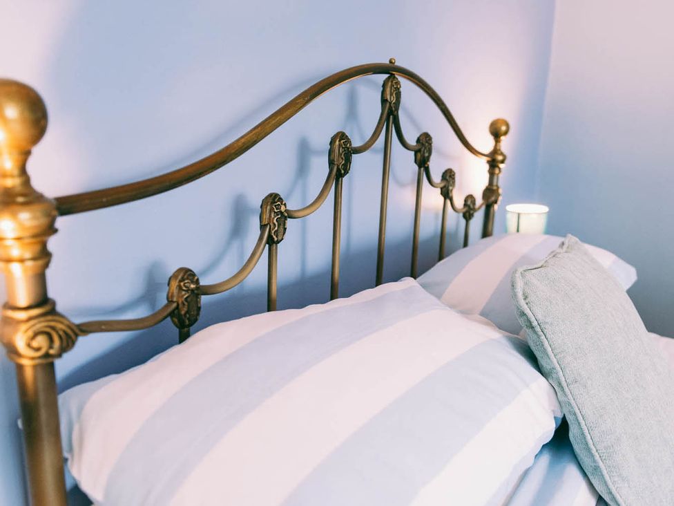 A bed with striped pillows and a light at 1 Bed Sleeps 3 Free Parking Pets Allowed Dereham
