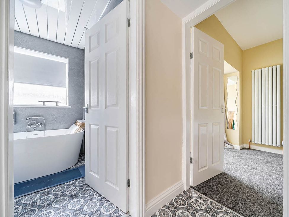 A bathroom with a bathtub and doors at Cottage Sleeps 6 with Parking and Garden in Bridlington