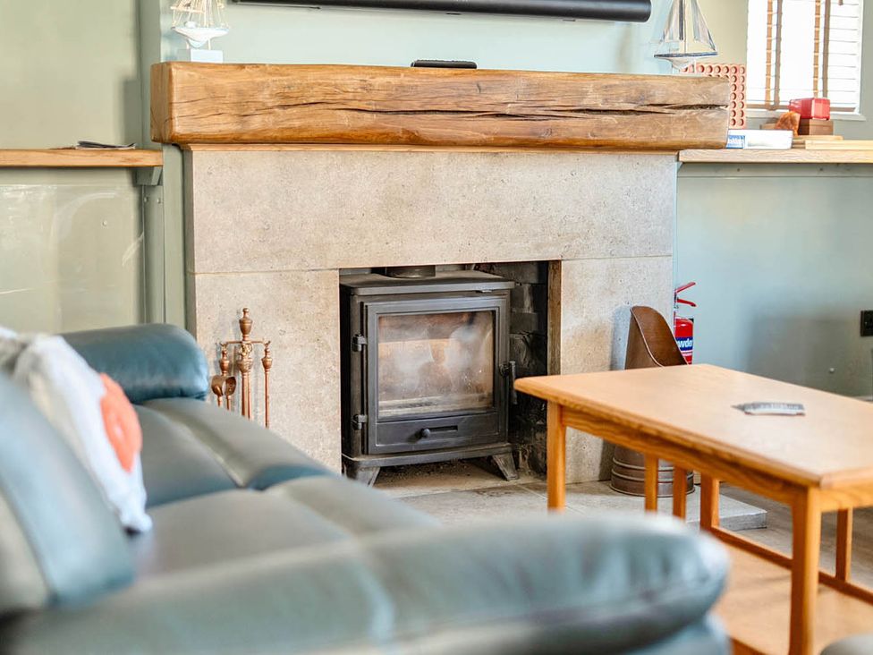 A living room with a fireplace and a wooden table at 4 Bed Sleeps 8 Pool Table Sea View Parking in Swanage