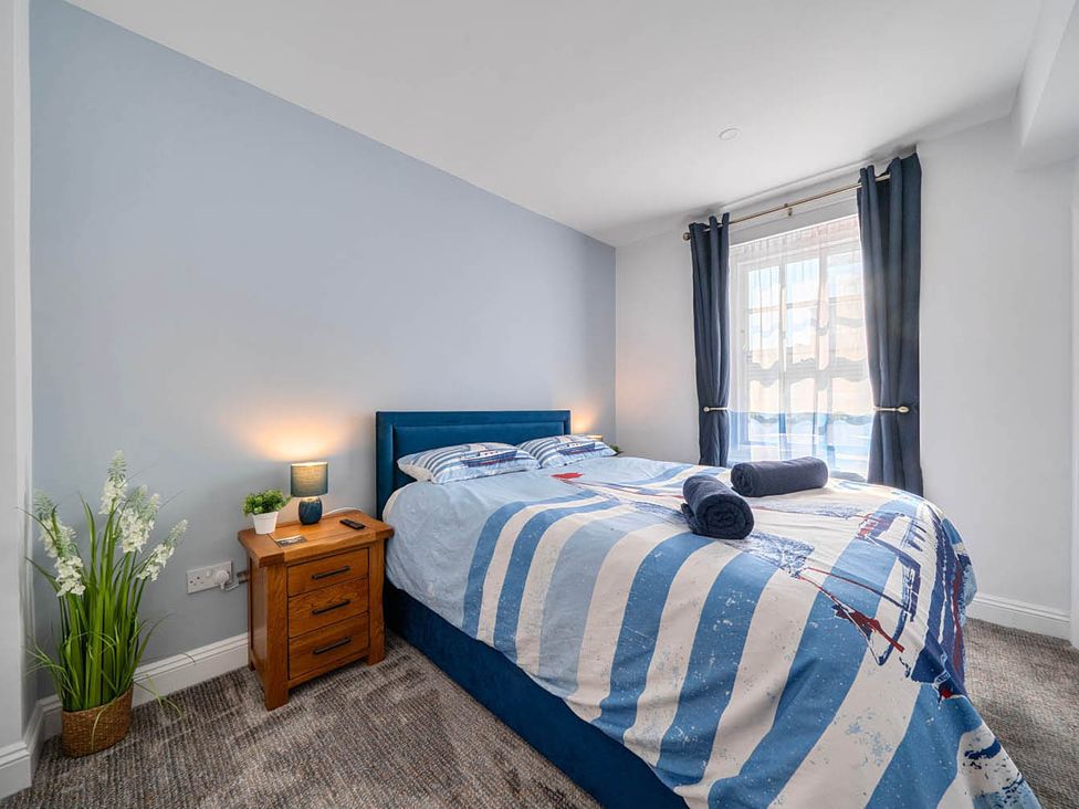 A bedroom with a bed, bedside table, and lamp at 4 Bed Sleeps 8 Pool Table Sea View Parking in Swanage