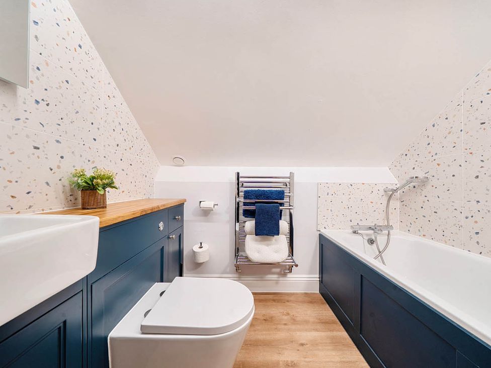 A bathroom with a sink, toilet, towel rack, and bath at 4 Bed Sleeps 8 Pool Table Sea View Parking in Swanage