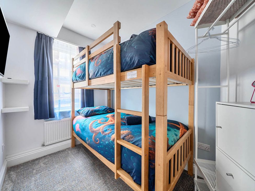 A bedroom with a bunk bed and a television at 4 Bed Sleeps 8 Pool Table Sea View Parking Swanage