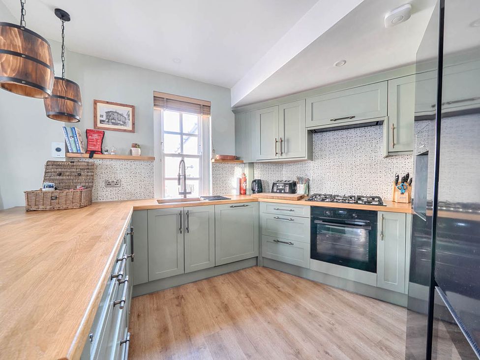 A kitchen with light green units and wooden countertop at 4 Bed Sleeps 8 Pool Table Sea View Parking Swanage