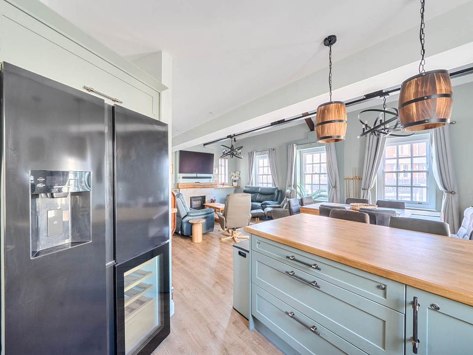 A kitchen with a refrigerator and dining area at 4 Bed Sleeps 8 Pool Table Sea View Parking in Swanage