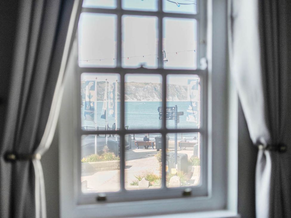 A window with a view of the ocean and pathway at 4 Bed Sleeps 8 Pool Table Sea View Parking in Swanage