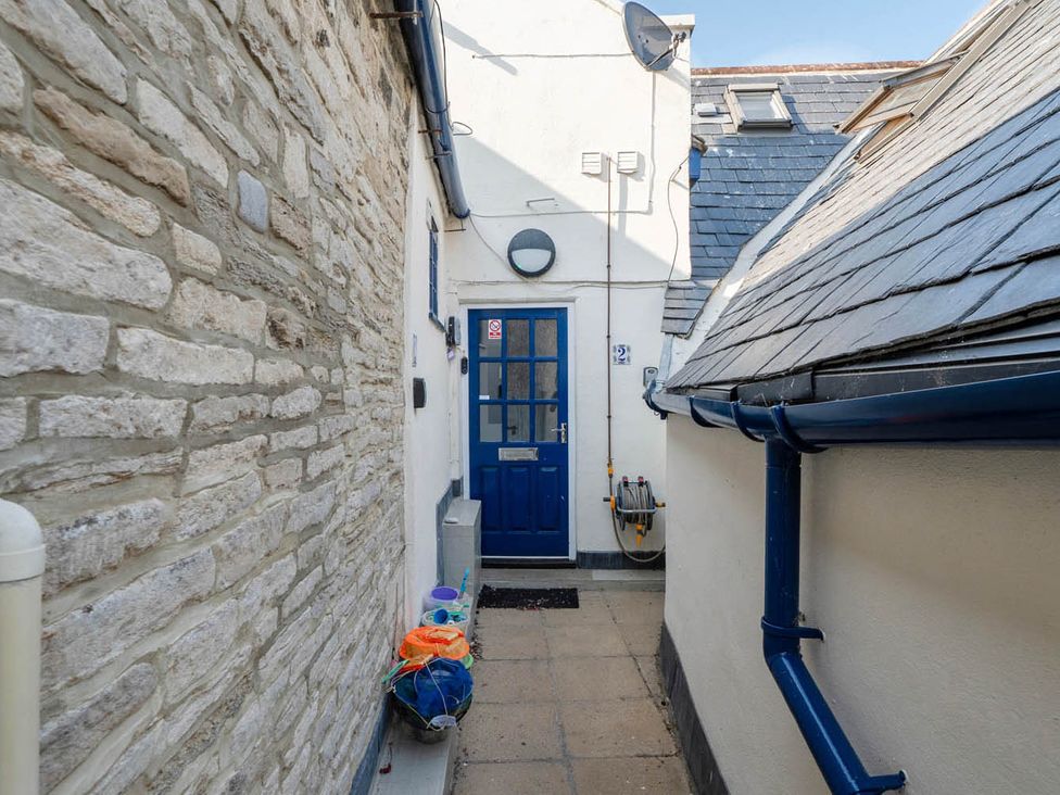 An outdoor pathway with a blue door and a stone wall at 4 Bed Sleeps 8 Pool Table Sea View Parking, Swanage