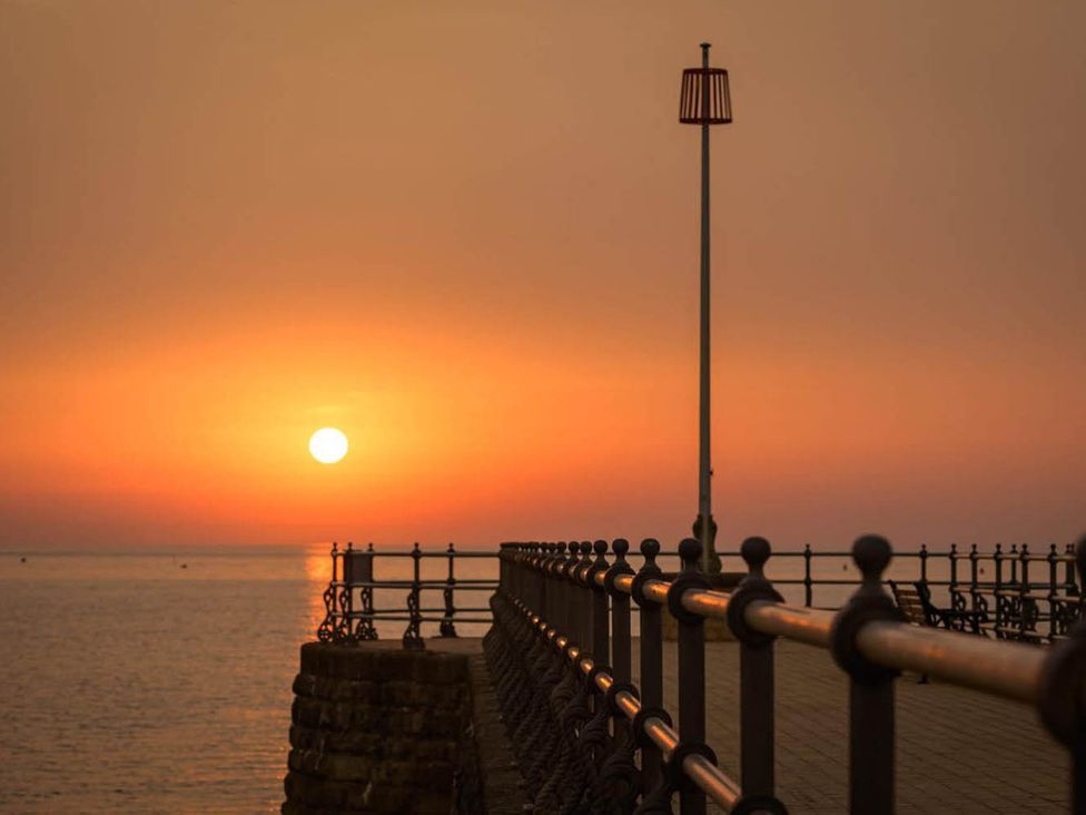 A pier with a railing at sunset at 4 Bed Sleeps 8 Pool Table Sea View Parking, Swanage