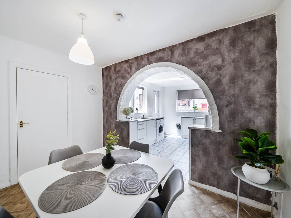 A dining room with a table and chairs leading to a kitchen at The Old Barn in Manchester