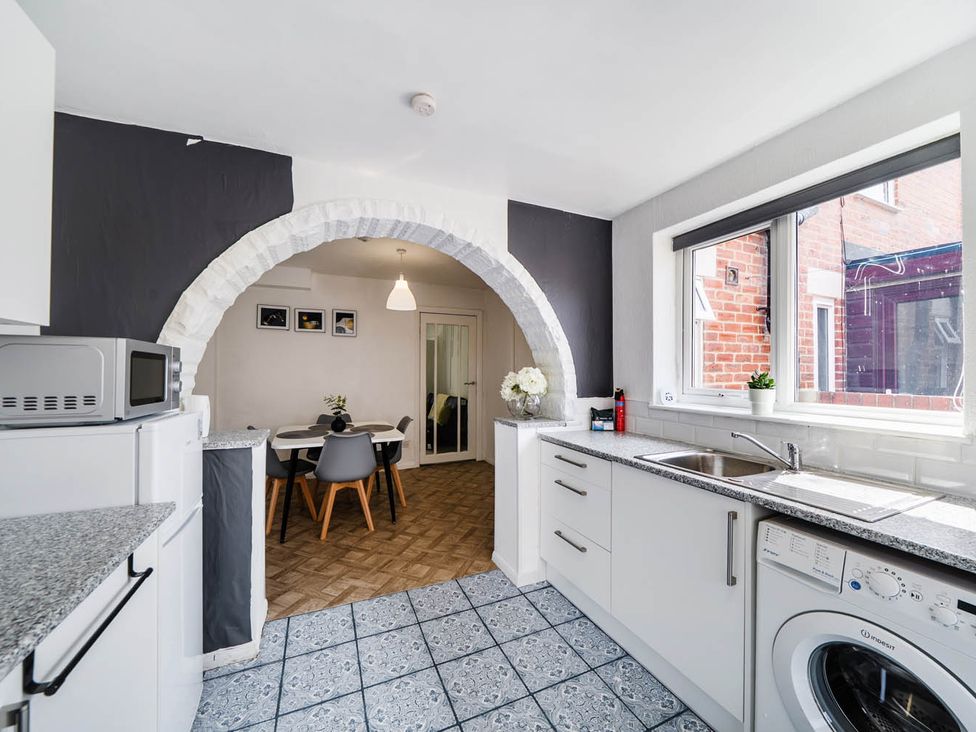 A kitchen with a sink and microwave leading to a dining area at a property