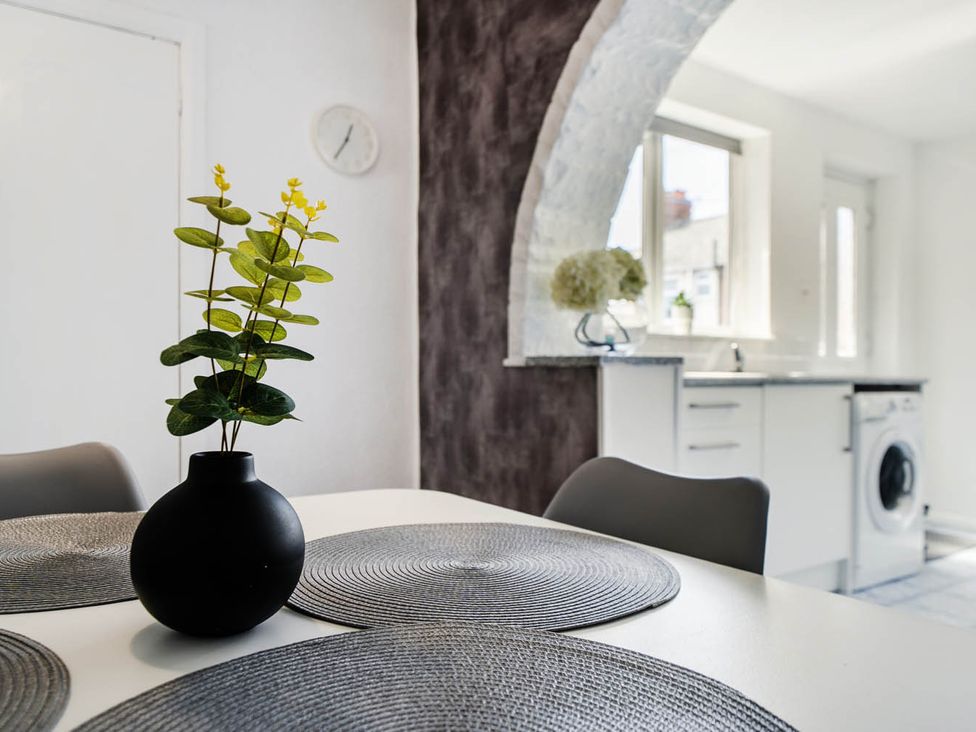 A kitchen with a table and a vase with a plant at the property