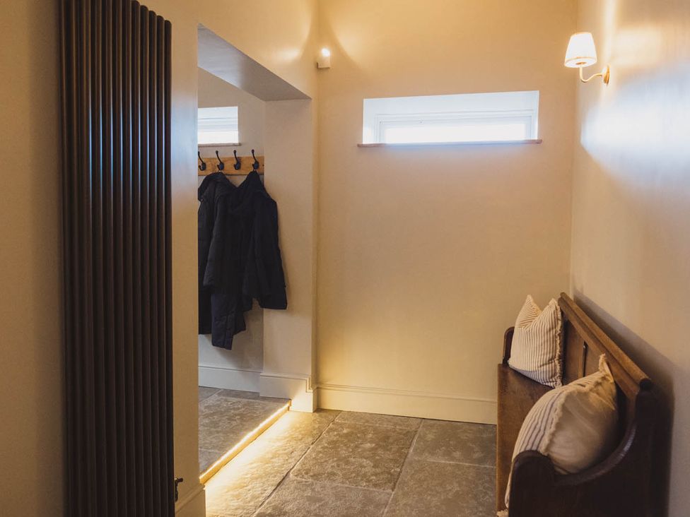 A hallway with a bench and coat hooks at 