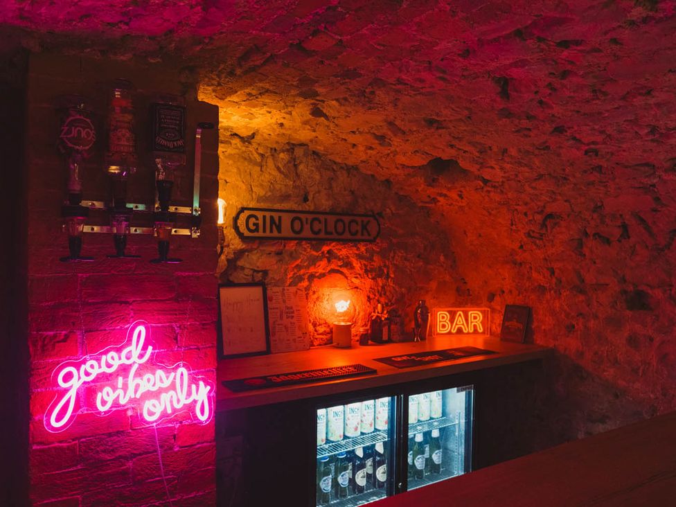 A home bar with a neon sign and gin dispenser at a private residence