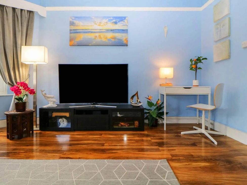 A living room with a television and flowers on a table at a property