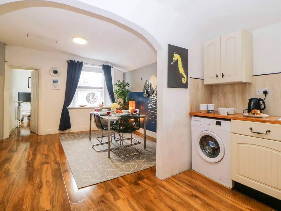 A kitchen with dining table and washer at The Old Barn in Manchester