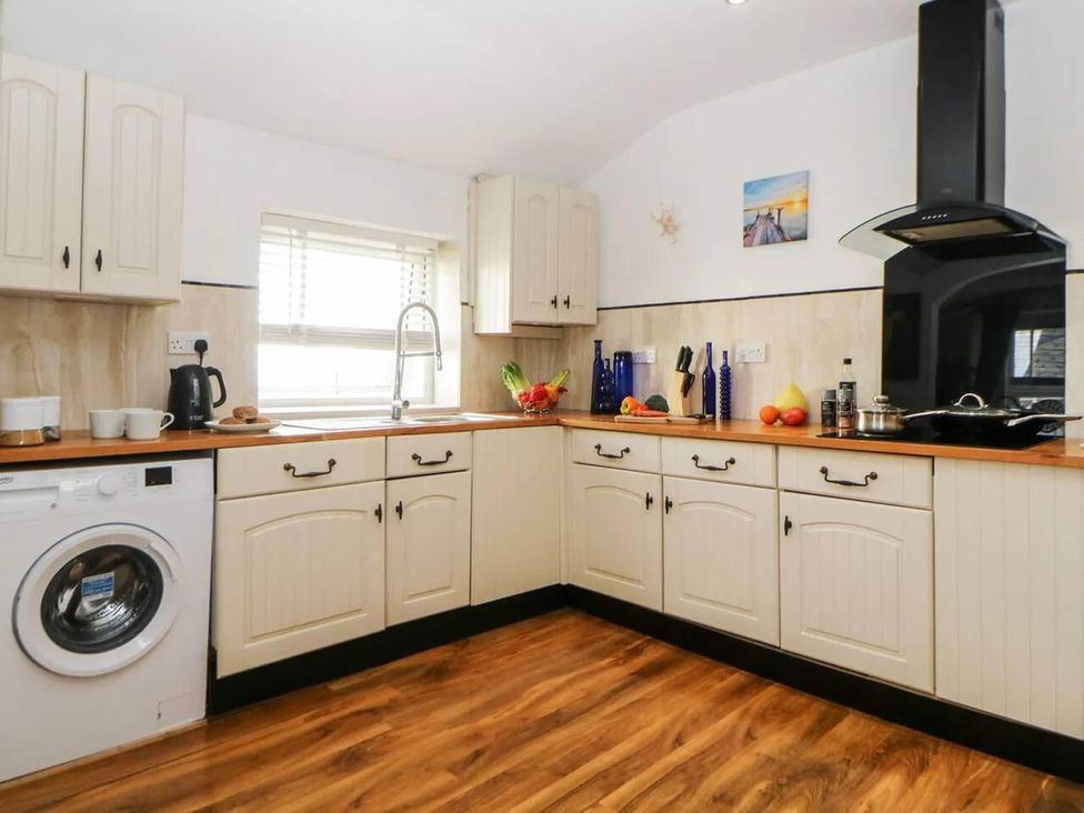 A kitchen with cabinets, sink, washing machine and countertop at The Old Barn in Manchester