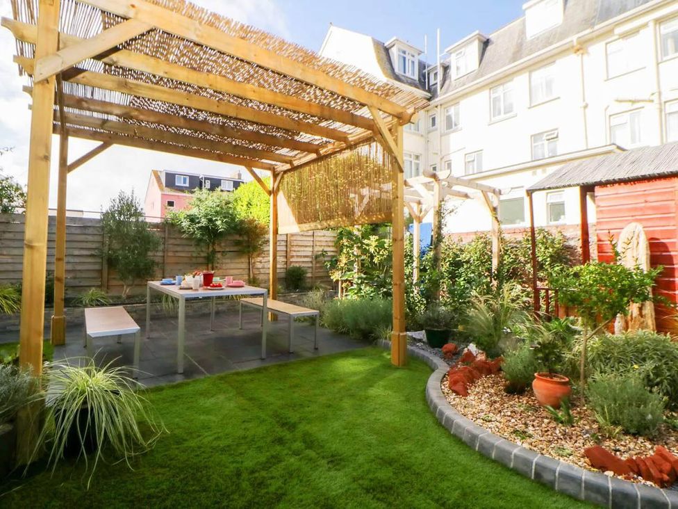 A garden with a wooden pergola and table at the property in location