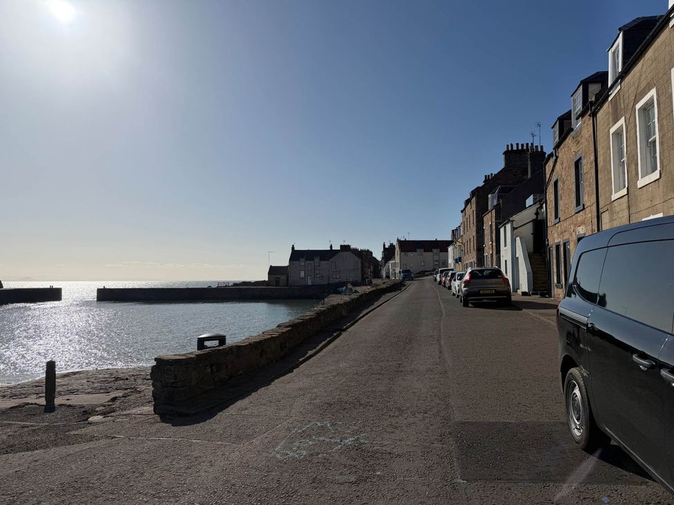 A coastal road with buildings and parked cars at an unknown location