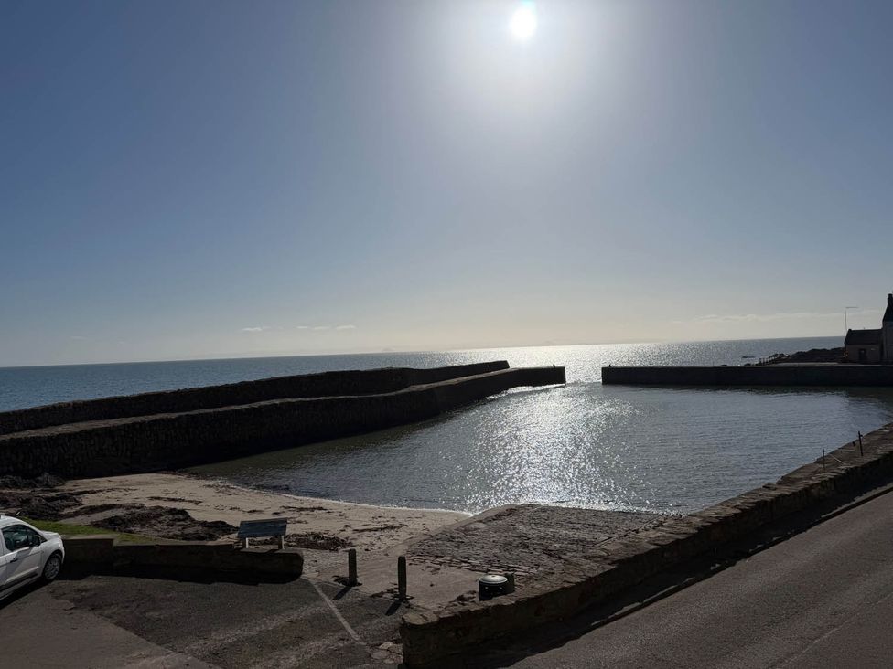 A view of a harbor and ocean with docks and a car nearby at an unspecified location