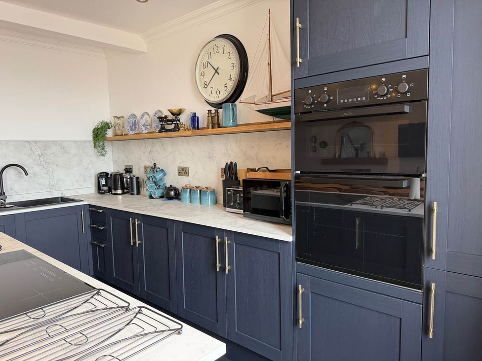 A kitchen with cabinets, sink, clock, and appliances at The Old Barn in Manchester