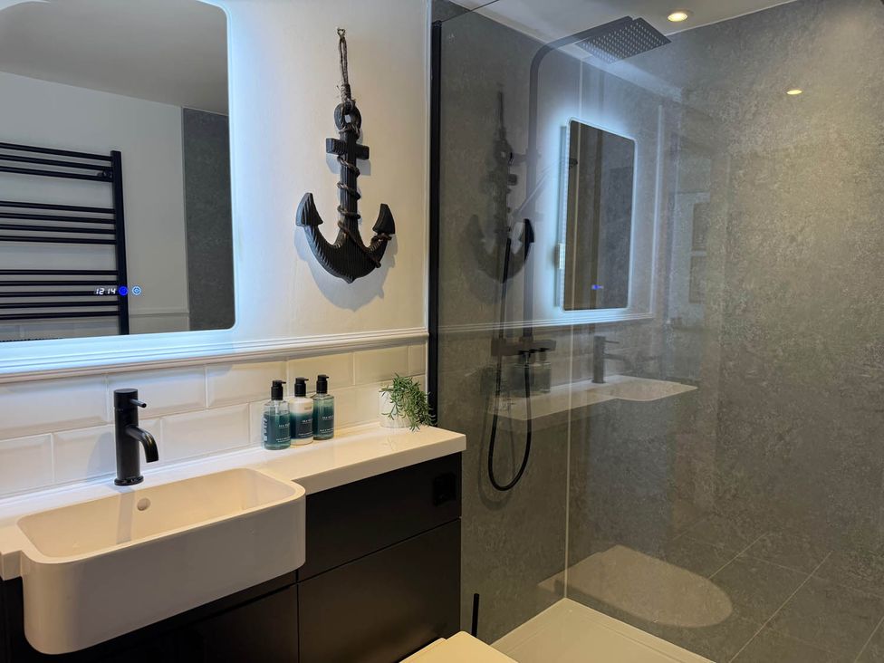 A bathroom with a sink, shower, and decorative anchor at 