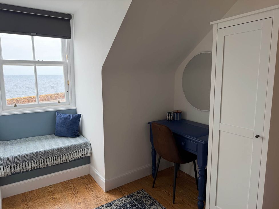 A bedroom with a desk and a sitting area by the window at 