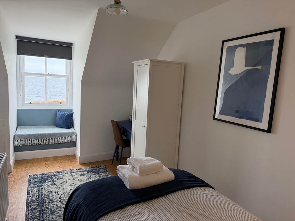 A bedroom with a window seat and desk at a seaside property