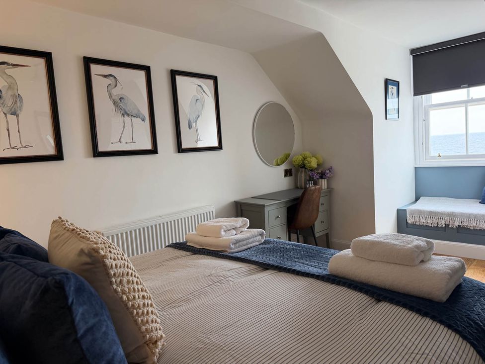 A bedroom with a bed, desk, and window at the seaside property