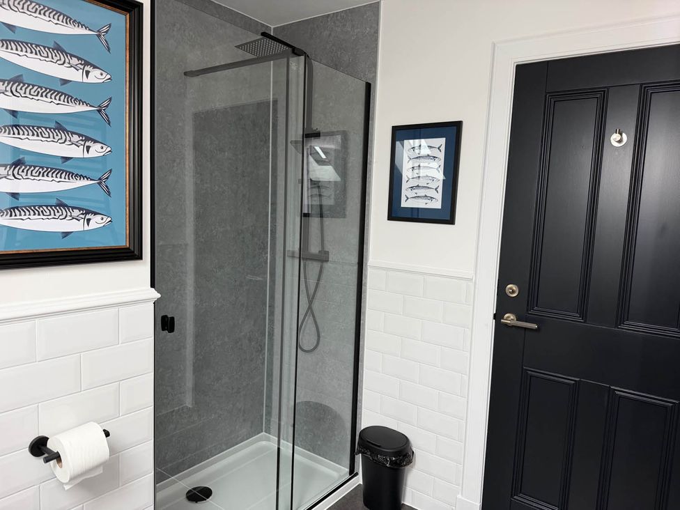 A bathroom with a shower and framed artwork at The Old Barn in Manchester