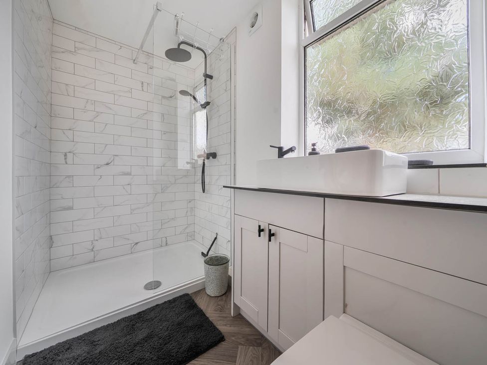 A bathroom with a shower, sink, and window at Annexe Bungalow Sleeps 2 Maximum Parking Garden in Scratby
