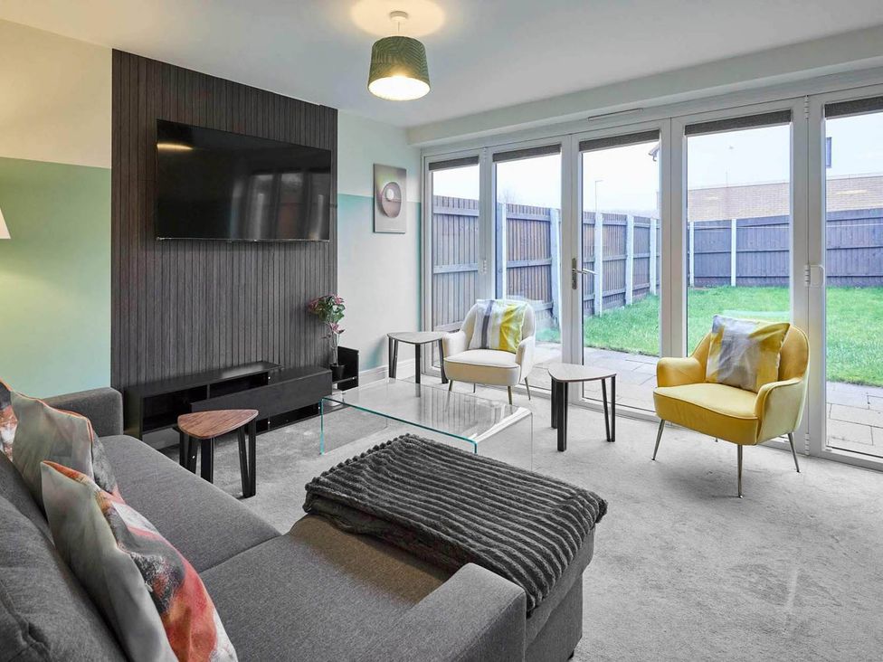 A living room with a sofa and television at House Sleeps 8 with WiFi in Corby