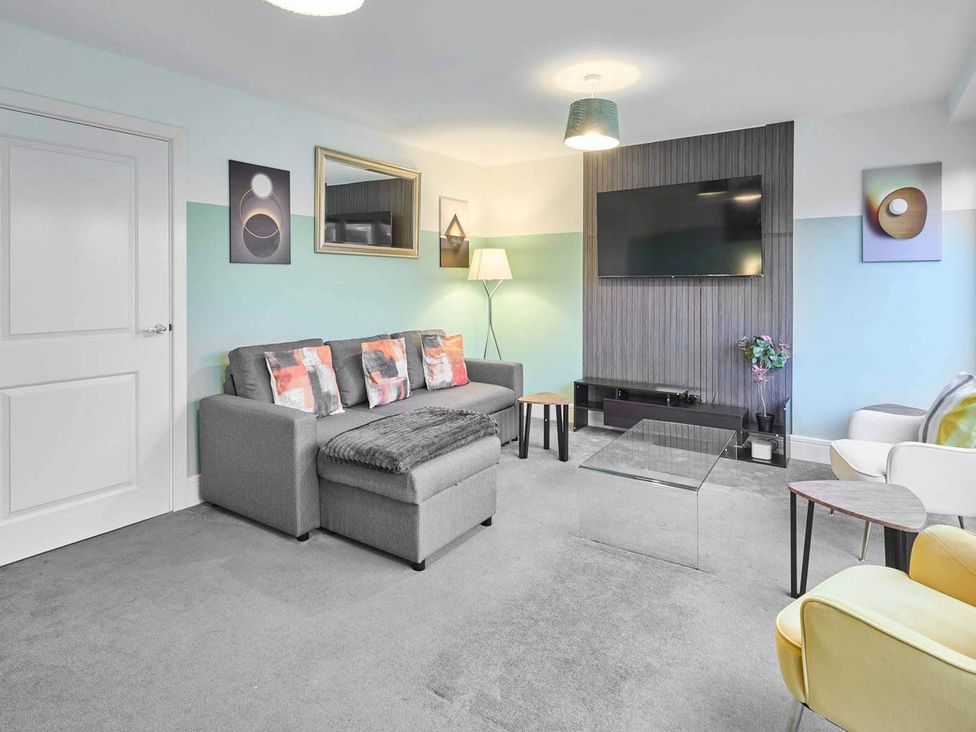 A living room with a sofa and television at House Sleeps 8 with WiFi in Corby