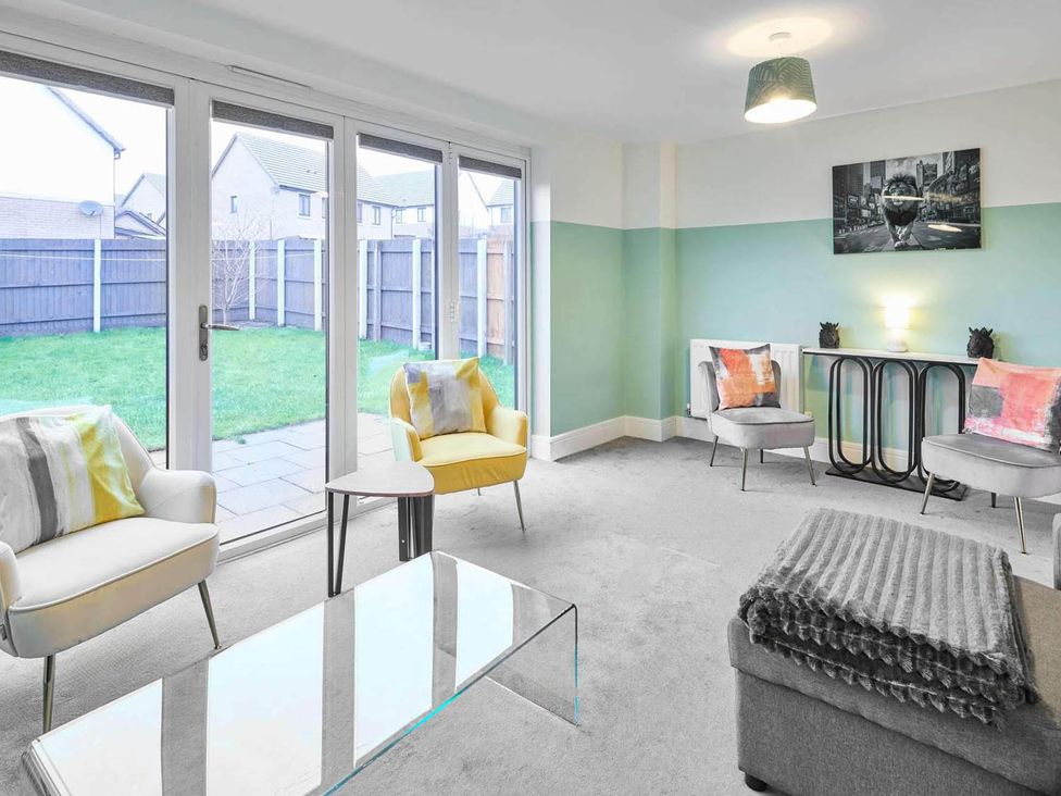 A living room with seating and a view of garden at House Sleeps 8 with WiFi in Corby