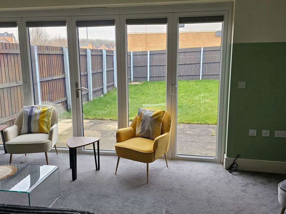 A living room with sliding doors leading to a fenced yard at House Sleeps 8 with WiFi in Corby