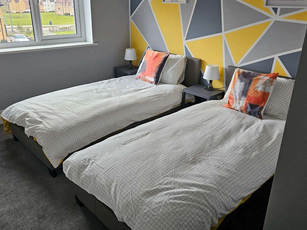 A bedroom with two single beds and a window at House Sleeps 8 with WiFi Corby