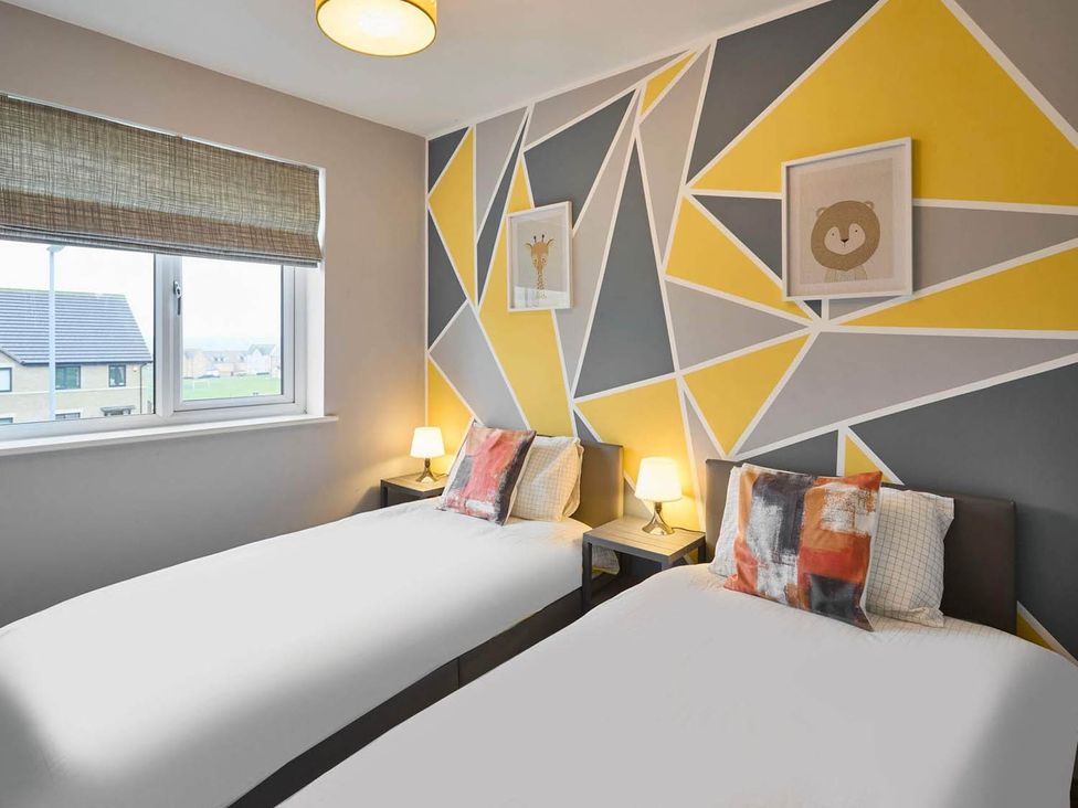 A bedroom with two beds and wall art at House Sleeps 8 with WiFi, Corby