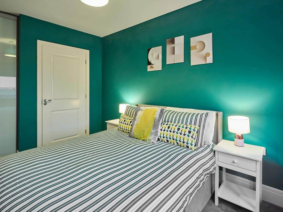 A bedroom with a bed and bedside tables at House Sleeps 8 with WiFi in Corby
