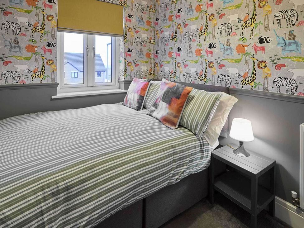 A bedroom with a bed and decorative wallpaper at House Sleeps 8 with WiFi in Corby
