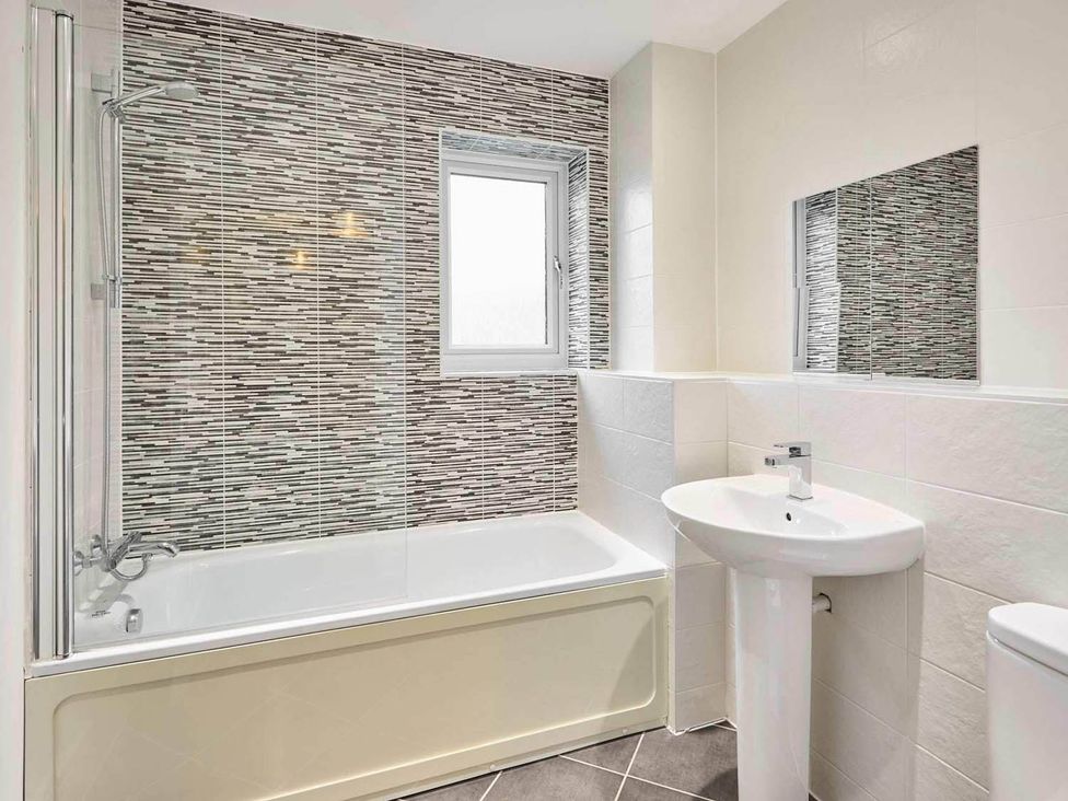 A bathroom with a bath tub and sink at House Sleeps 8 with WiFi Corby