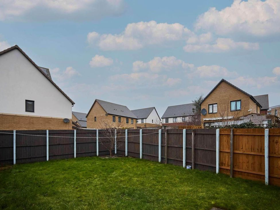A garden with grass and houses in the background at House Sleeps 8 with WiFi, Corby