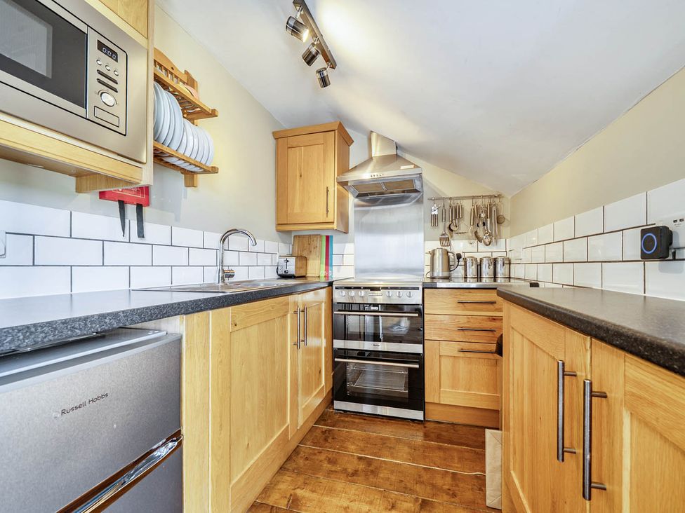 A kitchen with microwave, stove, sink, and utensils at Hayloft Sleeps 3 with Enclosed terrace in Dereham