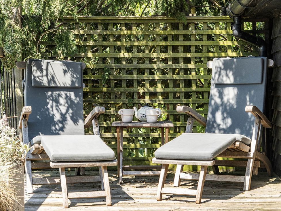 An outdoor seating area with deck chairs and a tea set at Hayloft Sleeps 3 with Enclosed terrace Dereham