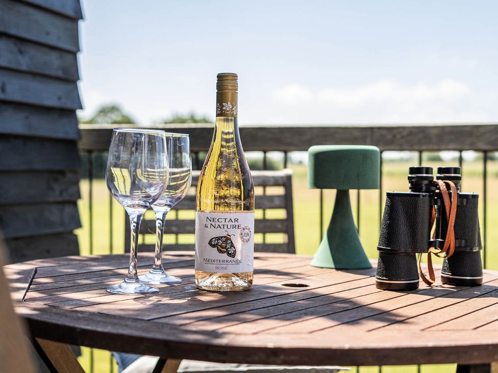 An outdoor terrace with wine, glasses, and binoculars at Hayloft Sleeps 3 with Enclosed terrace Dereham