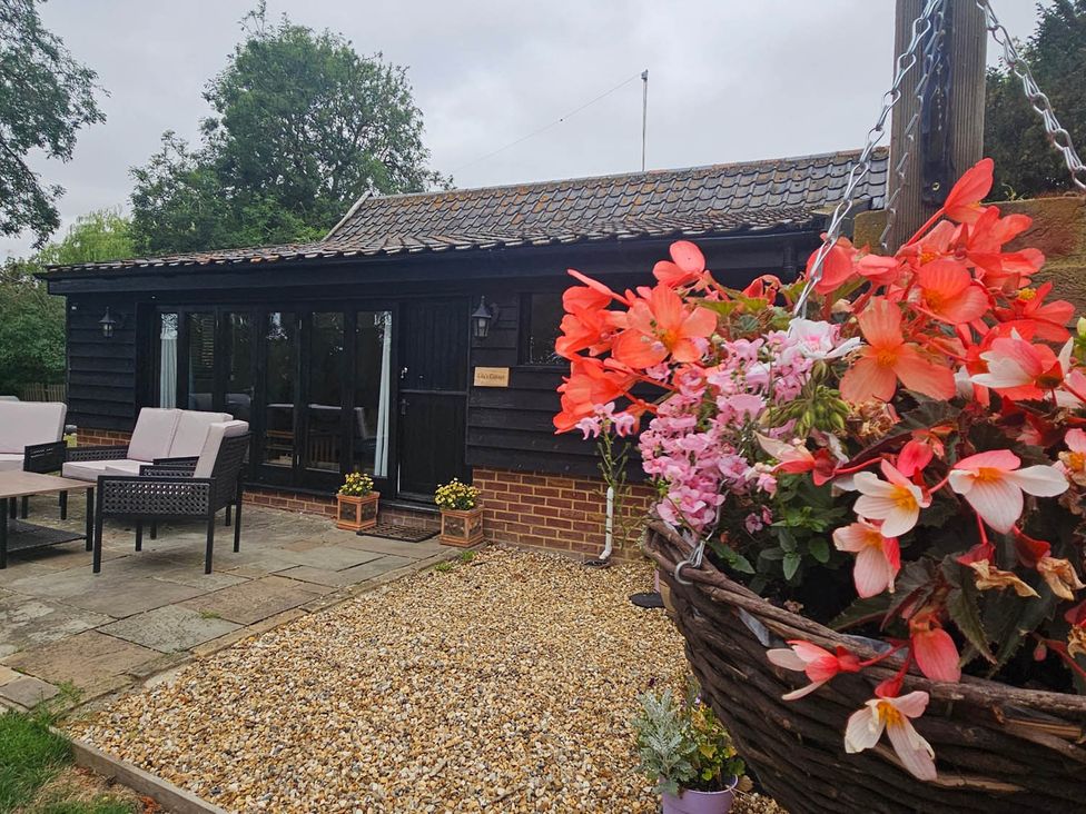 An outdoor seating area with a table and flowers at Lily's Cottage Suffolk Sleeps 2 with Pets Mendlesham Green near Stowmarket