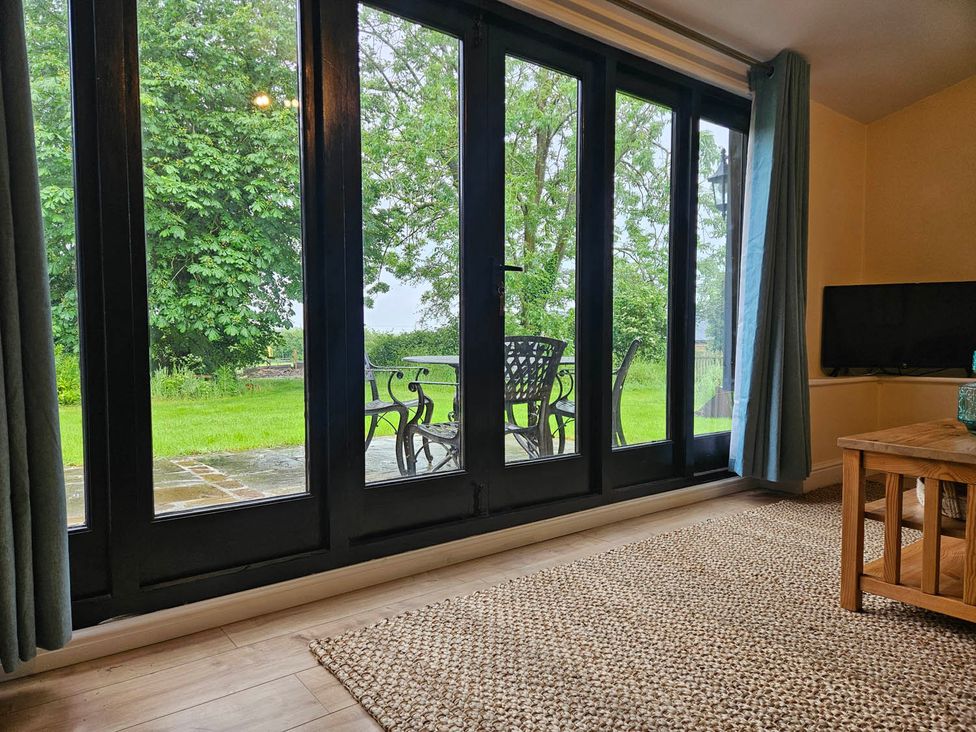 A living room with glass doors leading to outdoor furniture at Lily's Cottage Suffolk Sleeps 2 with Pets Mendlesham Green near Stowmarket