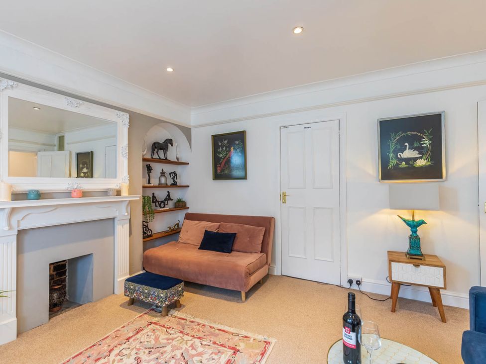 A living room with a sofa, mirror and shelves at Seafront Apartment Private Garden Free Parking Littlehampton