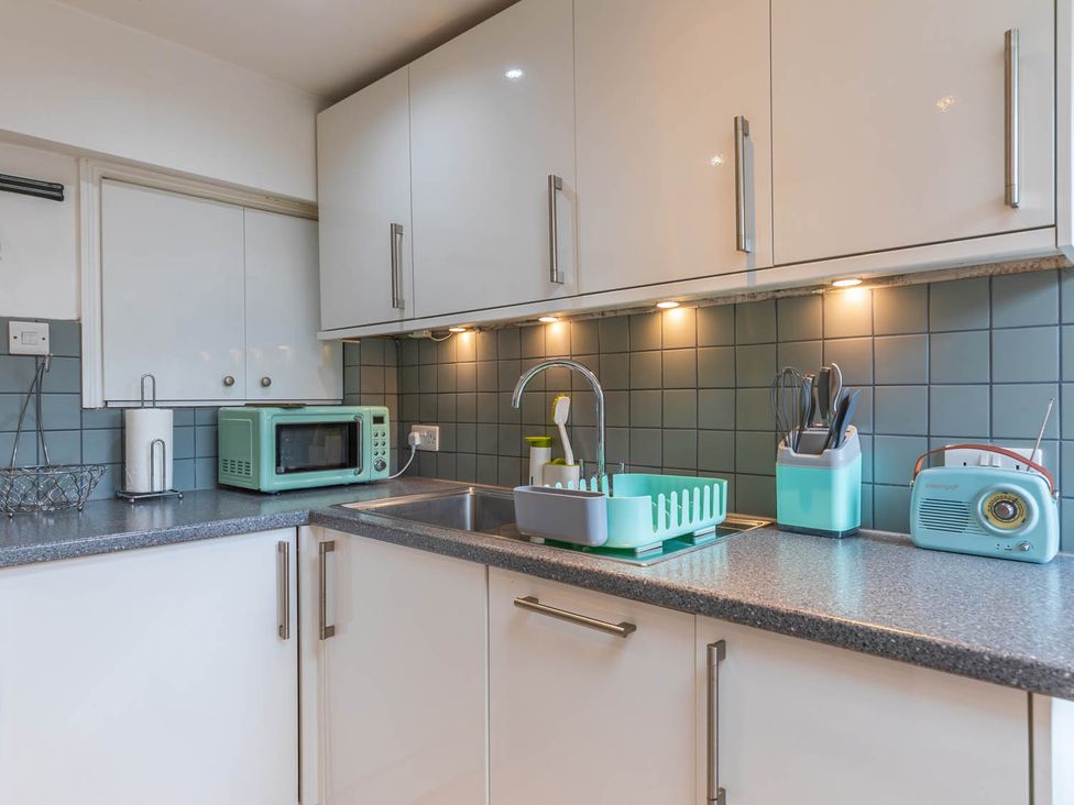 A kitchen with cabinets, sink, microwave and dish rack at Seafront Apartment Private Garden Free Parking Littlehampton